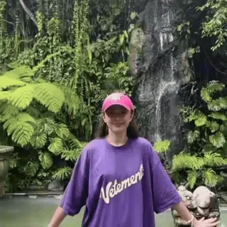 🫠 Vetements woman, purple shirt, pink cap, nature, waterfall, fashion, outdoor, long hair, vetements, portrait telegram sticker