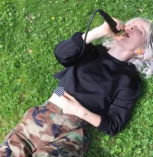 ❤️‍🔥 a3d4ff61 женщина, микрофон, пение, штаны камуфляж, трава, лежащая, на улице telegram sticker