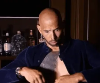 😢 34f62eb0 Andrew Tate uomo, calvo, tatuaggio, seduto, orecchini, cocktail telegram sticker